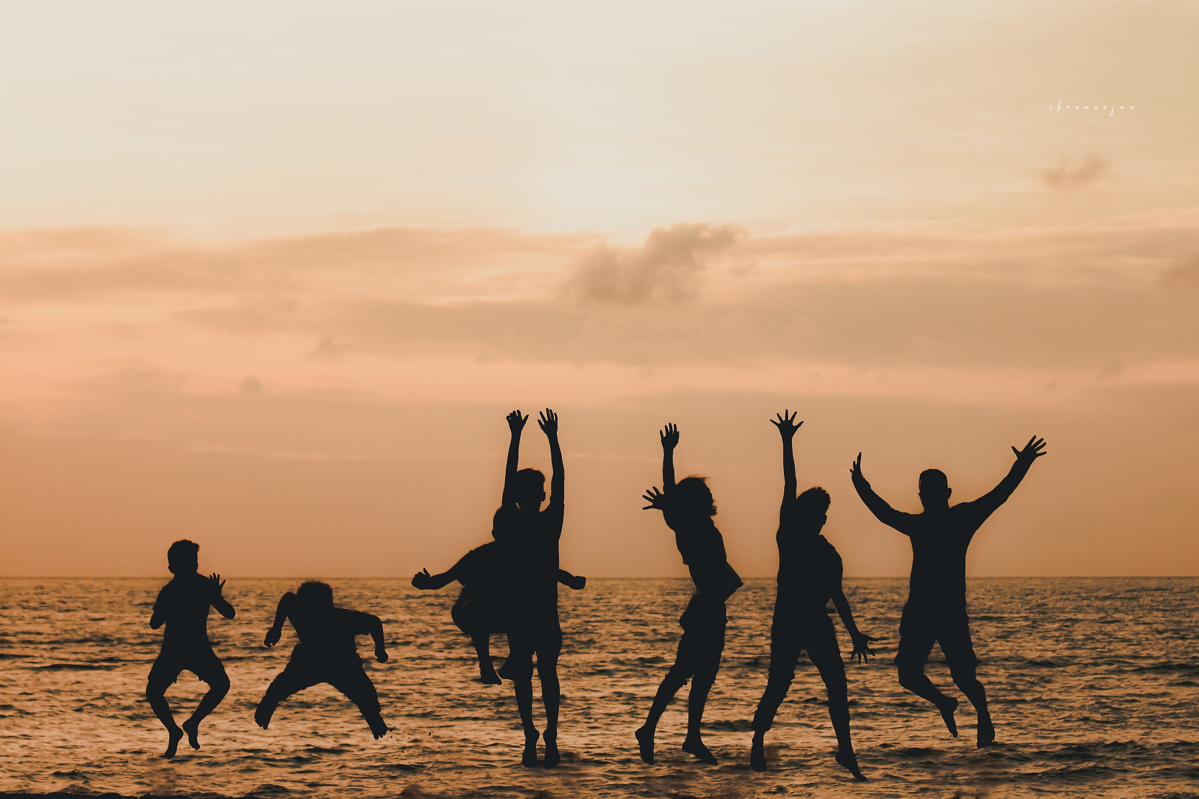 students jumping in the air at the beach at sunset