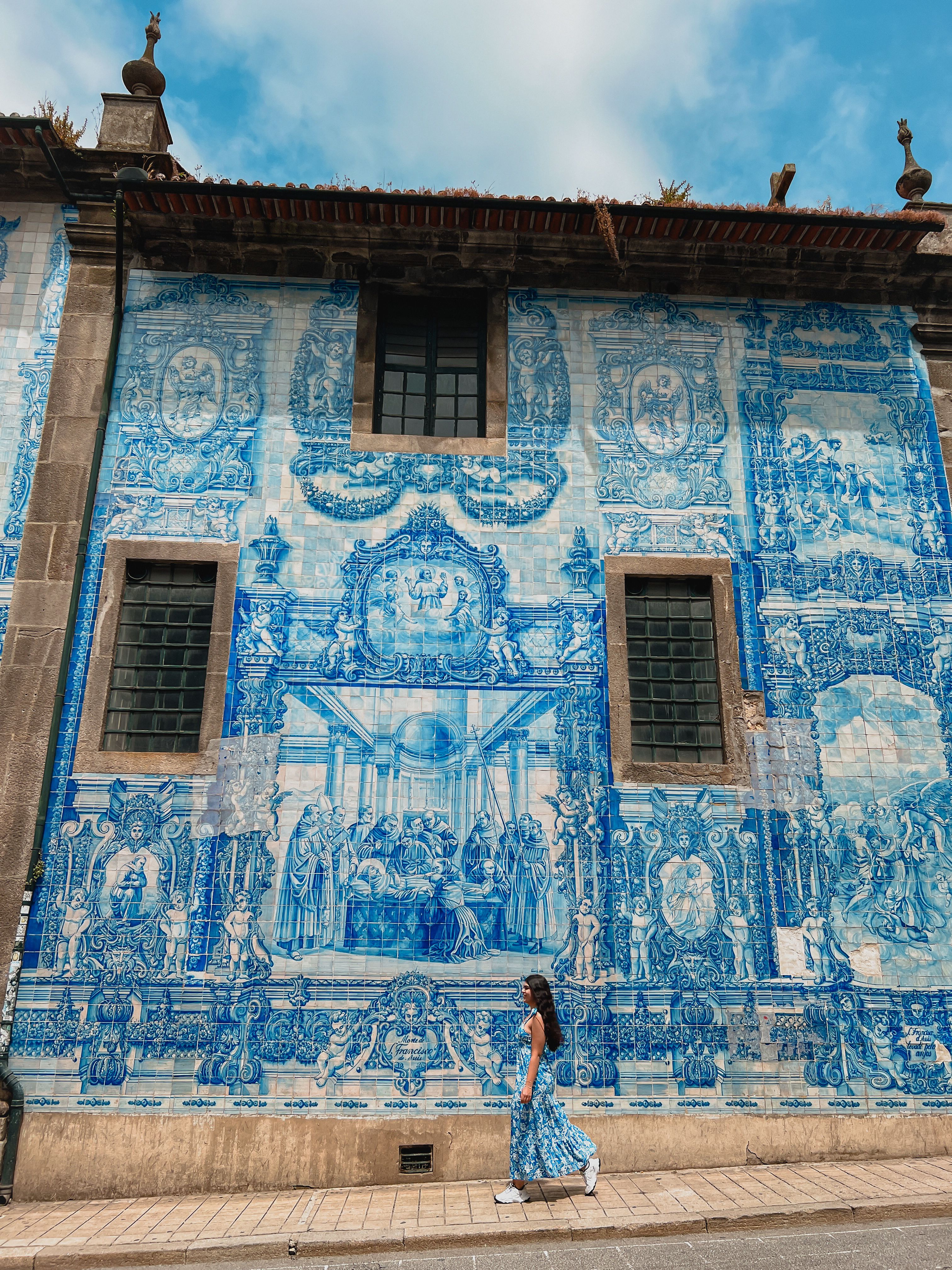 Ela is walking with a backdrop of a street mural. It's beautifully  painted, all blue and white