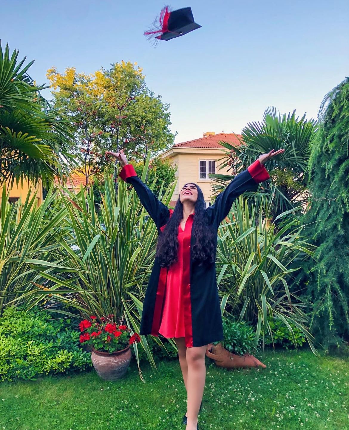 Ela is dressed in robes and has thrown a mortarboard in the air. 