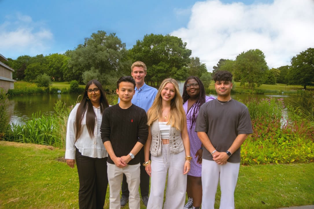Group of SU staff stood in front of the lake at Colchester Campus