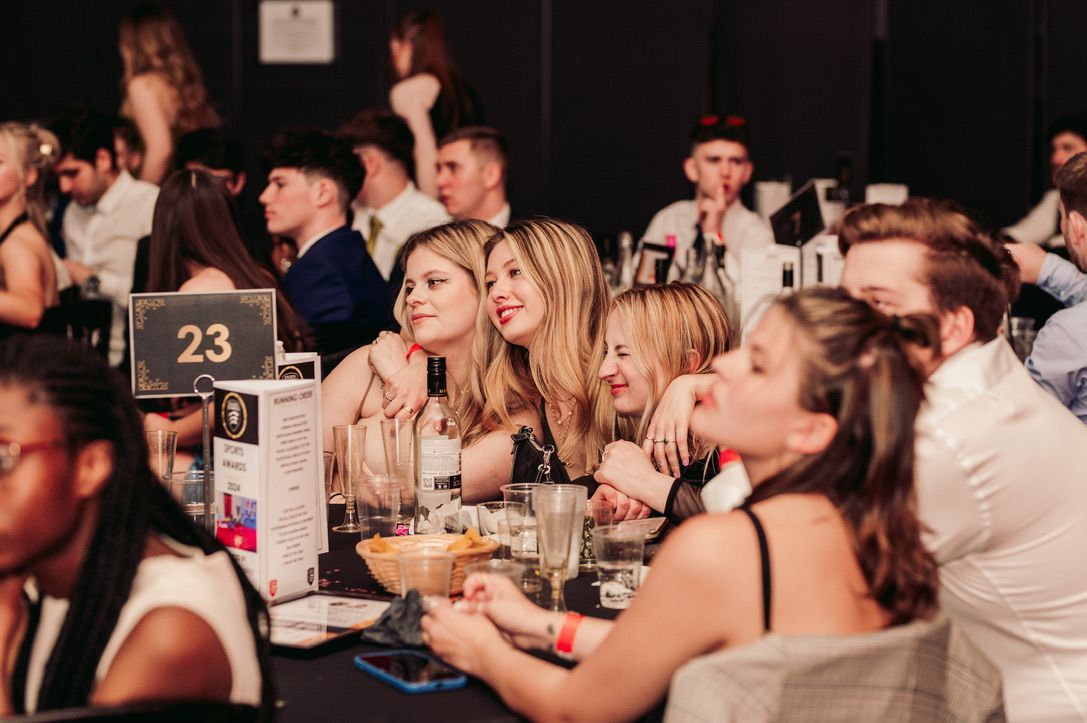 Group of students sat at a table at an awards ceremony, all smiling