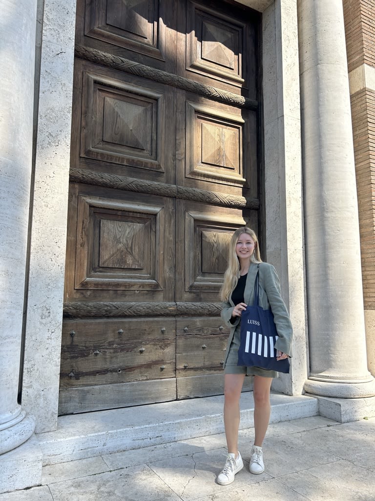 Lily-May stood in front of large, old wooden Italian doors