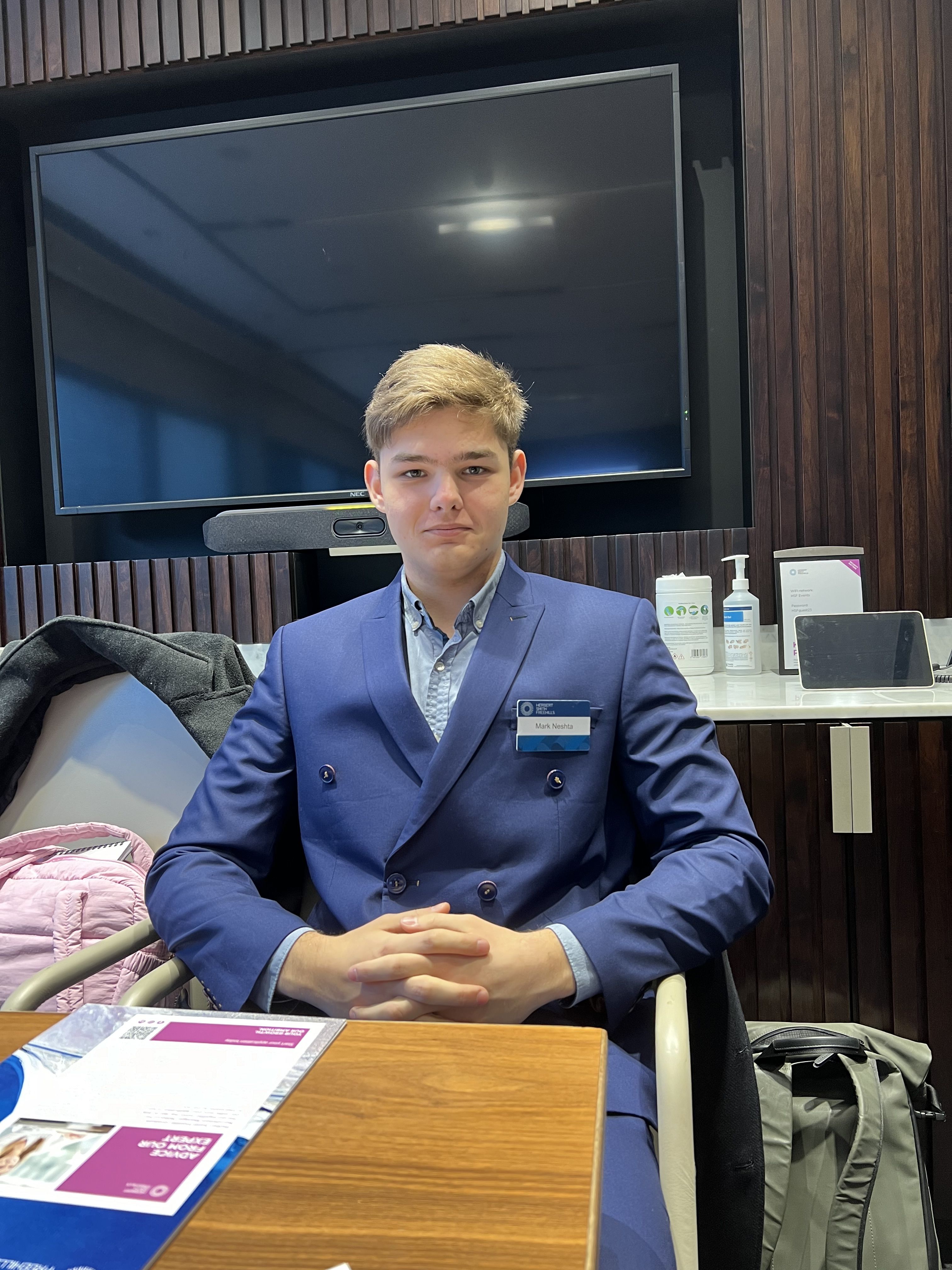 Mark is wearing a suit, sat at a desk during his visit to the International Criminal Court