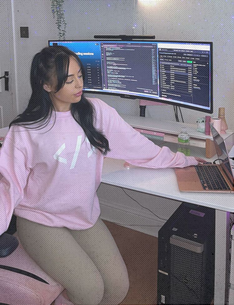 Liv Grant sat at her desk with 3 screens and a laptop. There is coding visible on all screens,